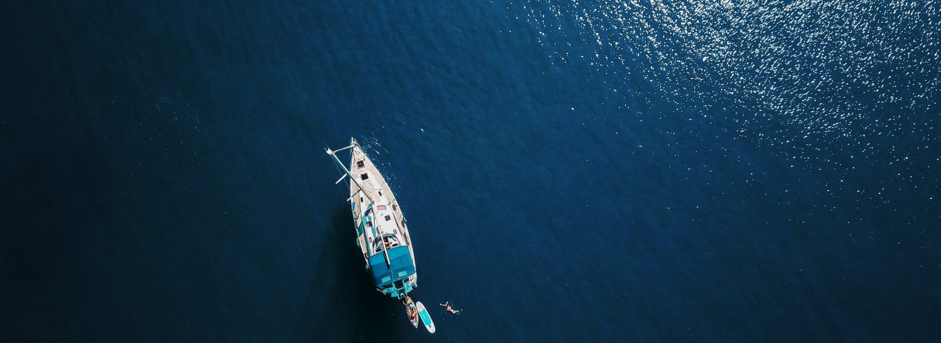 Aerial shot of beautiful blue lagoon at hot summer day with sailing boat. Top view.