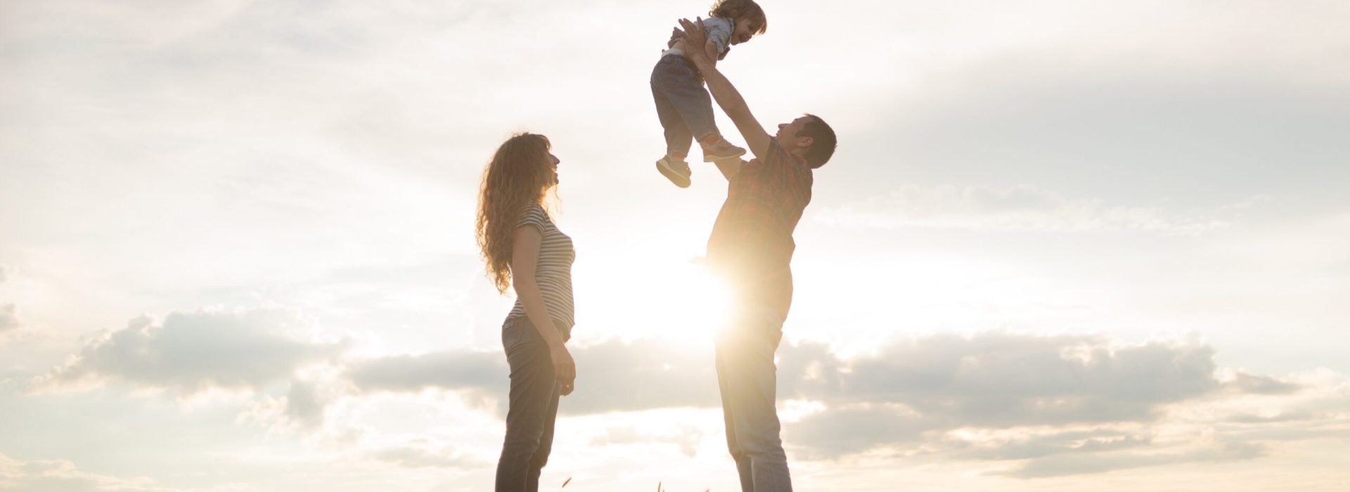 family mom dad and little son walk at sunset. Silhouettes of parents and toddler child on the background of the sky. Freedom and an active lifestyle